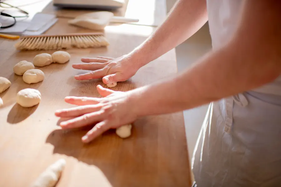 Hände formen Brötchen auf einem Holztisch