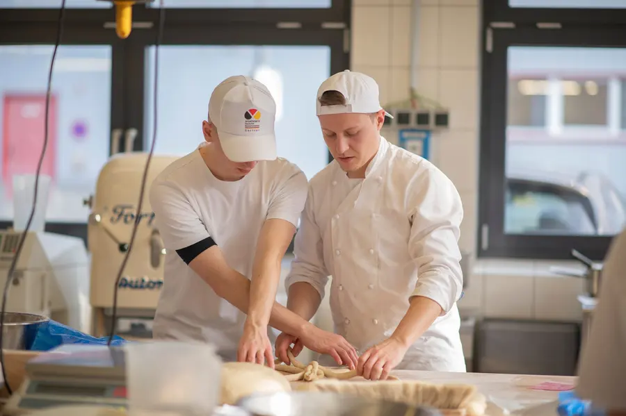 Zwei Bäcker arbeiten gemeinsam an einem geflochtenen Teig