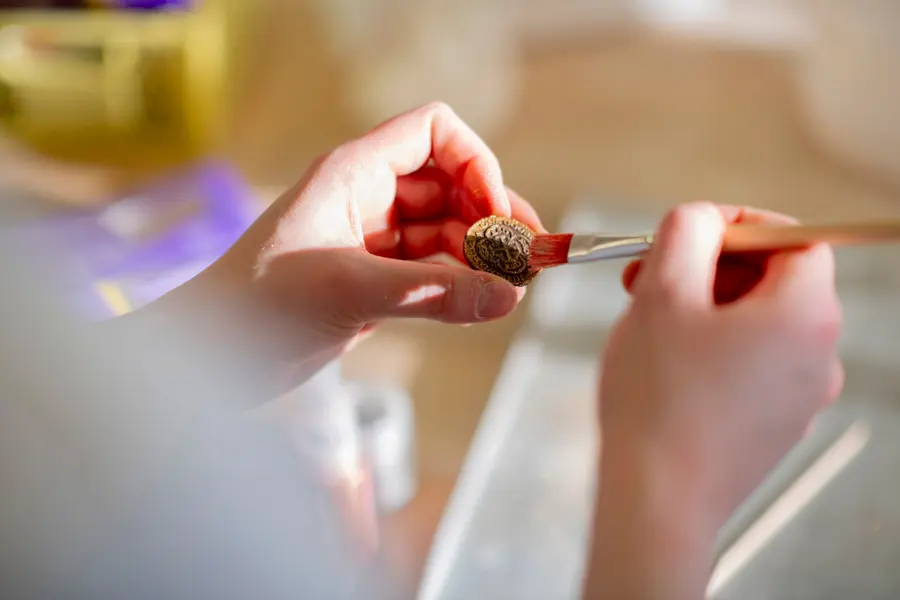 Nahaufnahme: Ein kleines Gebäckstück wird mit dem Pinsel bemalt