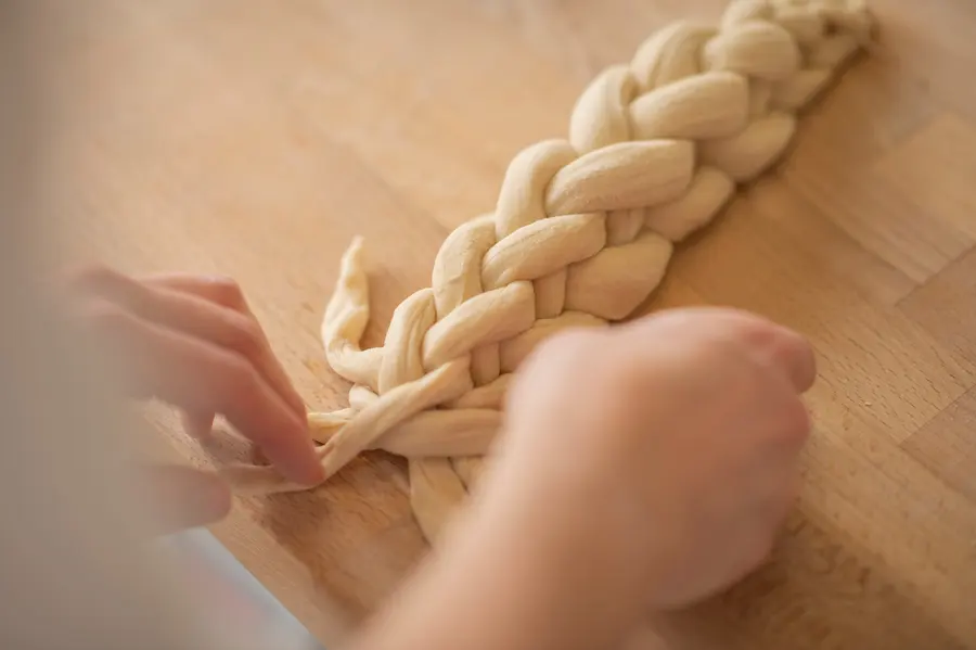 Hände flechten einen Hefezopf